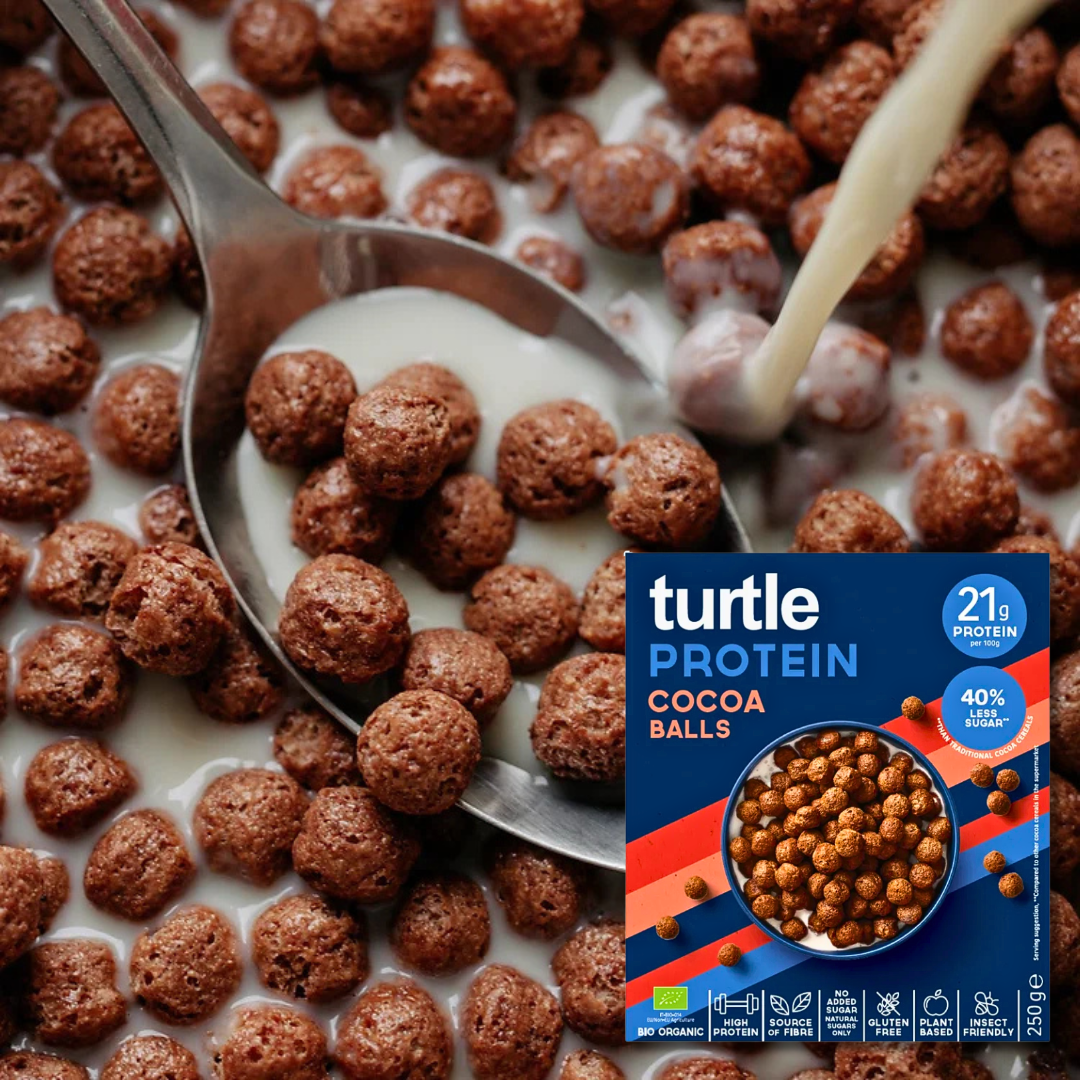 Close-up of Turtle Protein Cocoa Balls cereal in milk, with a spoon and milk being poured.
